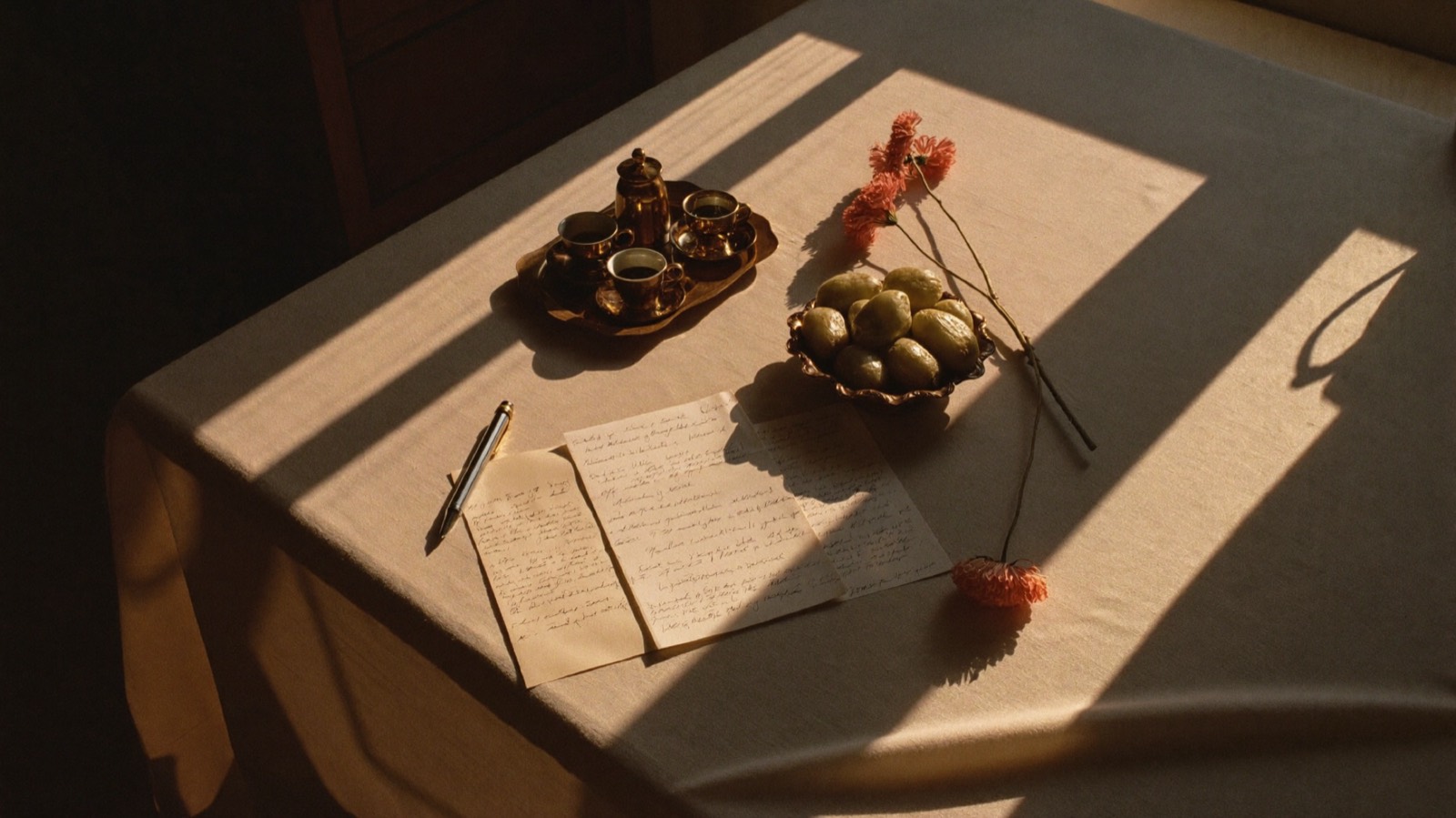 Golden evening light across a linen table holding a brass Arabic coffee set, a bowl of dates, handwritten notes and blush flowers